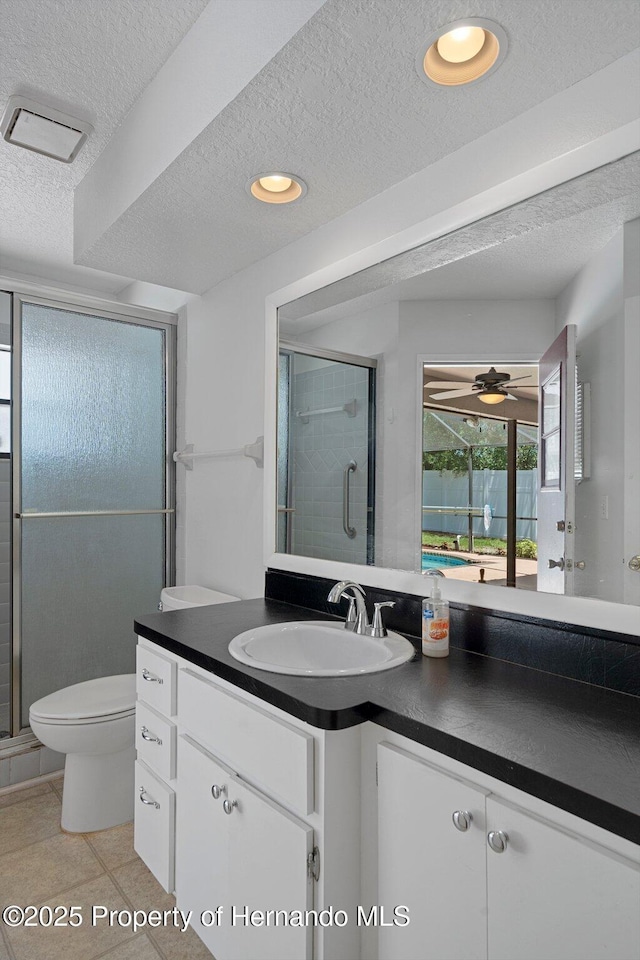 full bath featuring a stall shower, a textured ceiling, toilet, and vanity