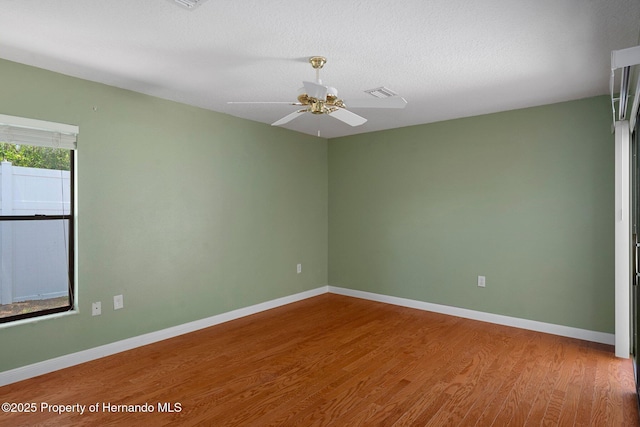 spare room with baseboards, wood finished floors, and visible vents