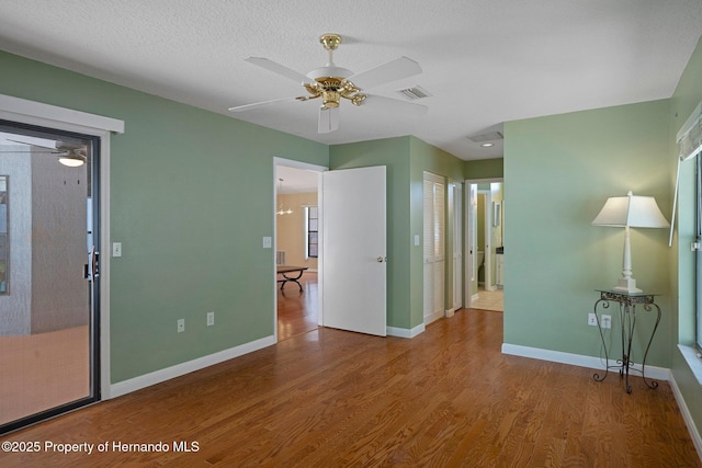 spare room with baseboards, a ceiling fan, wood finished floors, and visible vents