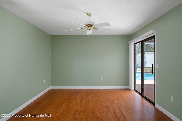 spare room with baseboards, a textured ceiling, ceiling fan, and wood finished floors