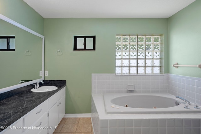 bathroom with a whirlpool tub, tile patterned floors, baseboards, and vanity