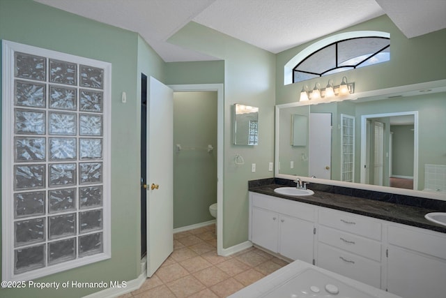 bathroom featuring baseboards, double vanity, toilet, and a sink