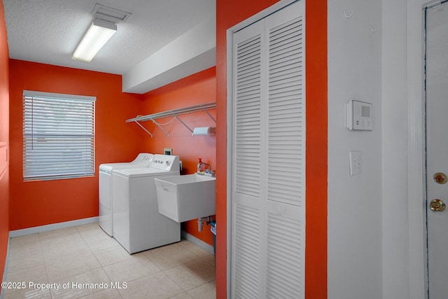 laundry area featuring washer and dryer, laundry area, a sink, a textured ceiling, and baseboards