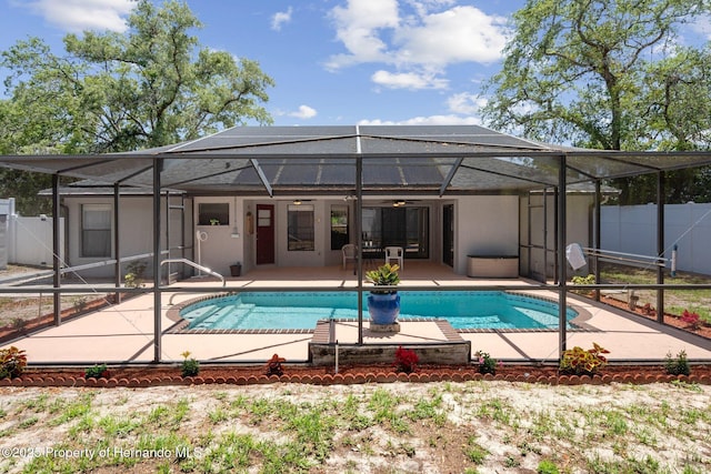 view of swimming pool with fence, a fenced in pool, a ceiling fan, a patio, and glass enclosure