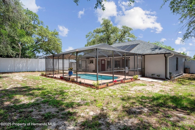 back of property featuring a lanai, a patio area, a fenced in pool, a fenced backyard, and a shingled roof