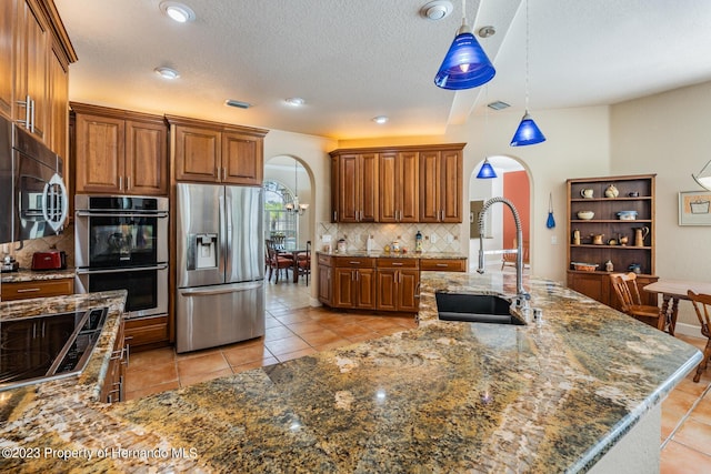 3011 Endsley Rd, Brooksville, FL 34604 - kitchen with a sink, stainless steel appliances, brown cabinetry, arched walkways, and tasteful backsplash