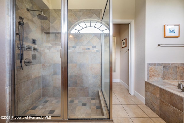 3011 Endsley Rd, Brooksville, FL 34604 - bathroom featuring a bath, baseboards, tile patterned flooring, and a shower stall