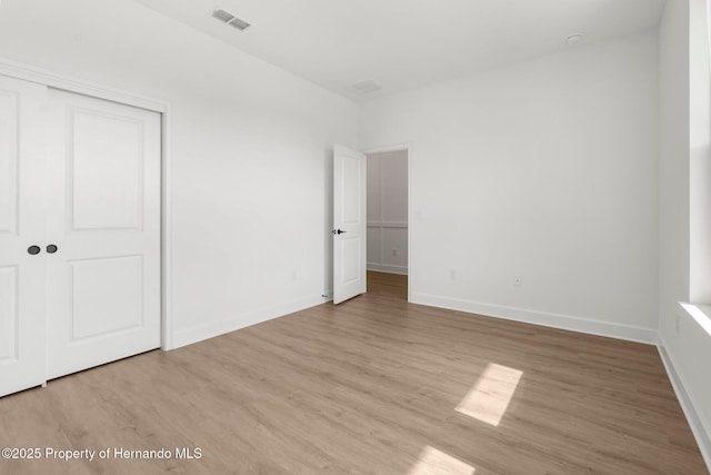 14042 Amero Ln, Spring Hill, FL 34609 - unfurnished bedroom with a closet, visible vents, wood finished floors, and baseboards