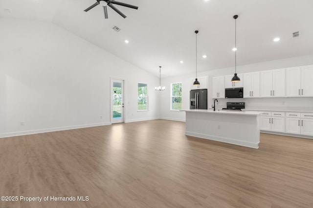 14042 Amero Ln, Spring Hill, FL 34609 - kitchen with ceiling fan with notable chandelier, open floor plan, high vaulted ceiling, black appliances, and white cabinets