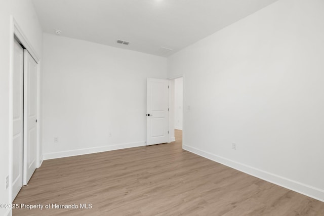 14042 Amero Ln, Spring Hill, FL 34609 - unfurnished bedroom with baseboards, a closet, visible vents, and light wood-style floors