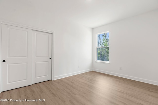 14042 Amero Ln, Spring Hill, FL 34609 - unfurnished bedroom with a closet, light wood-style floors, and baseboards