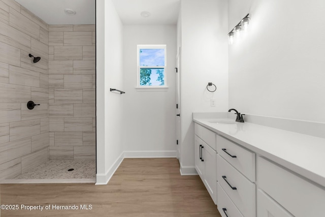 14042 Amero Ln, Spring Hill, FL 34609 - bathroom with vanity, wood finished floors, baseboards, and a tile shower