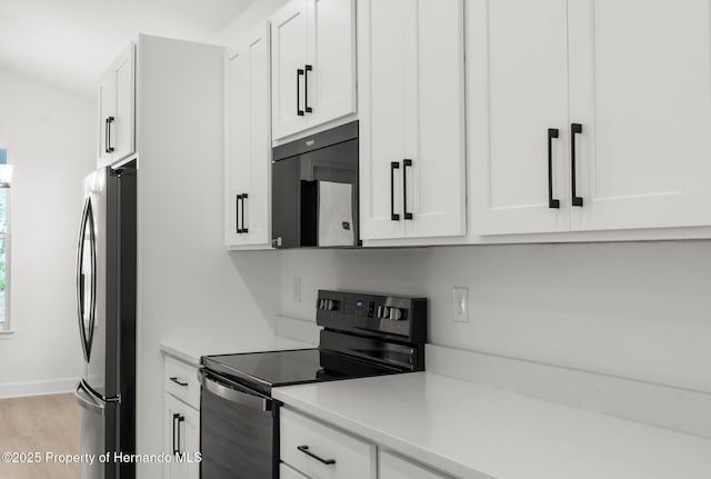 14042 Amero Ln, Spring Hill, FL 34609 - kitchen with light wood finished floors, white cabinets, baseboards, black appliances, and light countertops