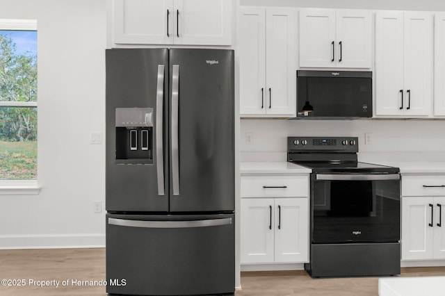 14042 Amero Ln, Spring Hill, FL 34609 - kitchen with stainless steel refrigerator with ice dispenser, light wood-style flooring, black microwave, light countertops, and electric stove