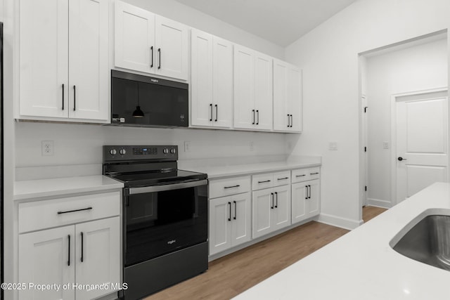 14042 Amero Ln, Spring Hill, FL 34609 - kitchen featuring electric range, light wood finished floors, black microwave, light countertops, and white cabinets