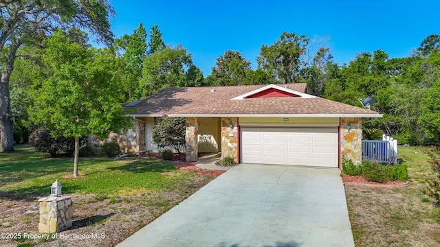single story home featuring a garage, a front yard, stone siding, and concrete driveway
