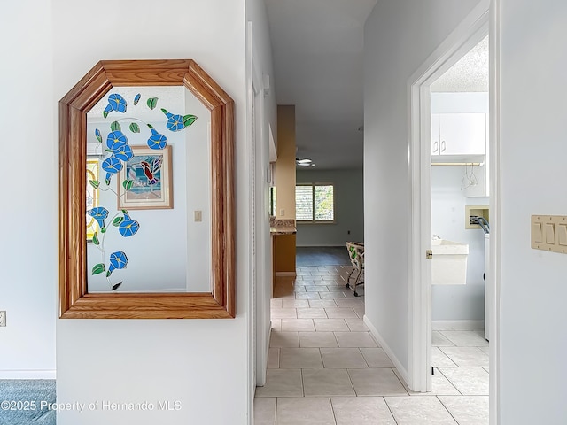 corridor with light tile patterned floors and baseboards