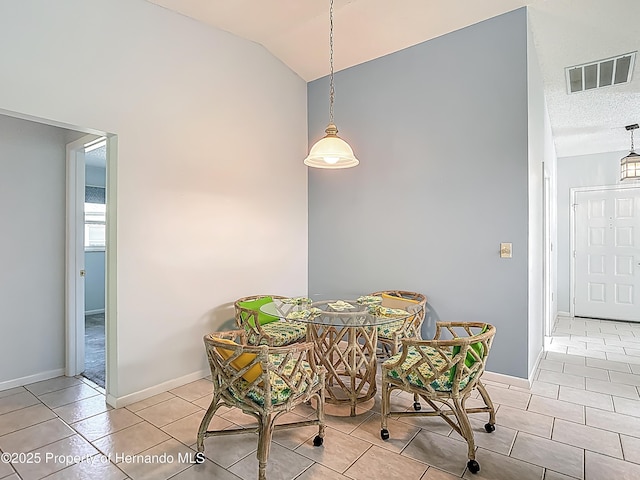 tiled dining room featuring baseboards, visible vents, and vaulted ceiling