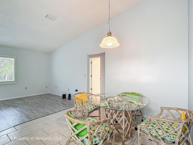 dining space with visible vents, baseboards, and vaulted ceiling