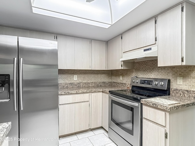 kitchen with under cabinet range hood, stainless steel appliances, light tile patterned floors, and backsplash