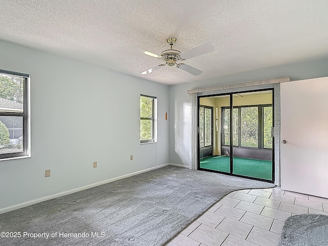 empty room featuring baseboards, a textured ceiling, light carpet, and ceiling fan