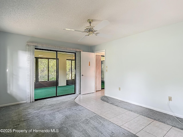 tiled empty room featuring baseboards, a ceiling fan, a textured ceiling, and carpet floors