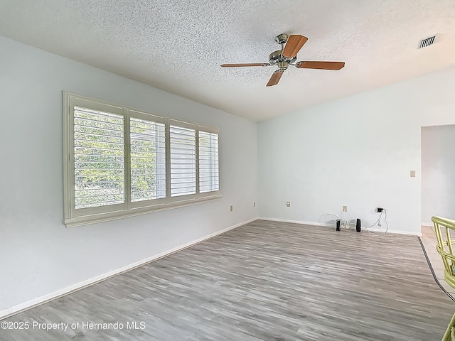 spare room with plenty of natural light, a ceiling fan, a textured ceiling, and visible vents