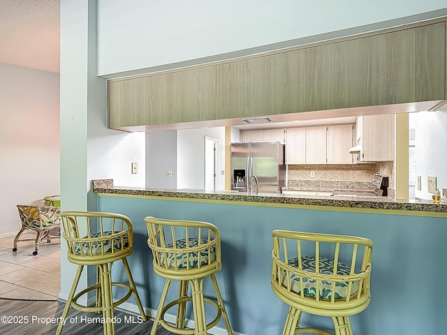 kitchen featuring dark countertops, appliances with stainless steel finishes, tasteful backsplash, tile patterned floors, and under cabinet range hood