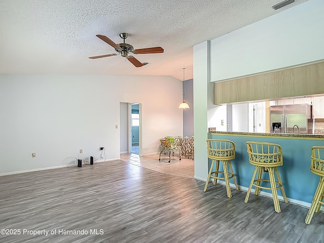 kitchen with visible vents, wood finished floors, stainless steel refrigerator with ice dispenser, a ceiling fan, and vaulted ceiling