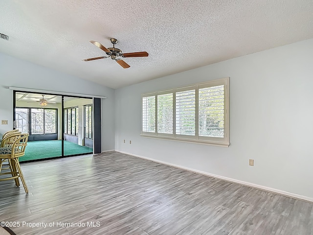 spare room with a textured ceiling, a healthy amount of sunlight, ceiling fan, and wood finished floors