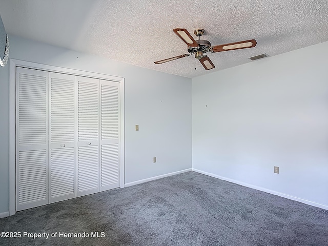 unfurnished bedroom with dark carpet, a ceiling fan, a textured ceiling, and a closet