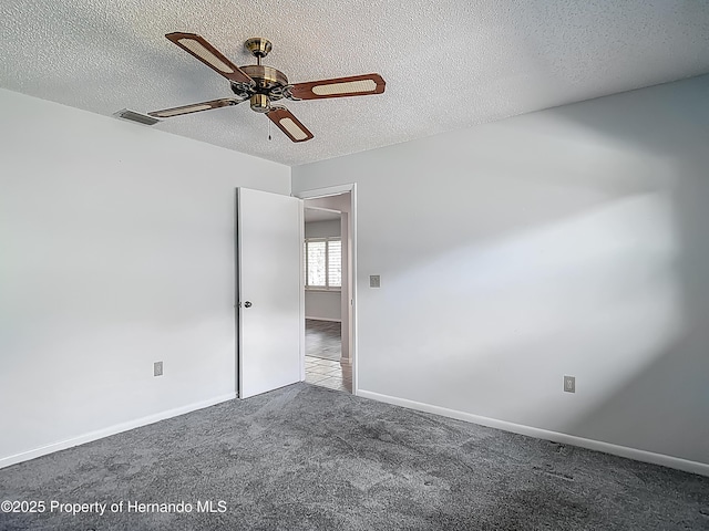 carpeted empty room featuring visible vents, a textured ceiling, ceiling fan, and baseboards