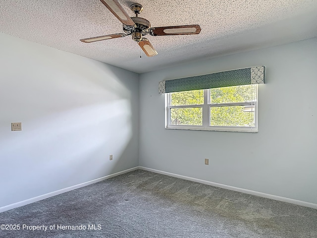 carpeted spare room with baseboards, a ceiling fan, and a textured ceiling