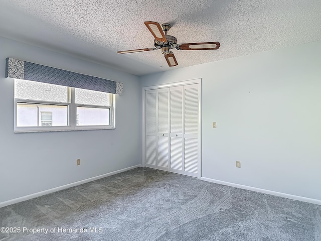 unfurnished bedroom with a textured ceiling, carpet, a ceiling fan, baseboards, and a closet