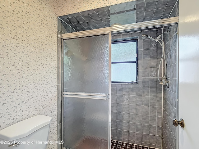 bathroom featuring a stall shower, toilet, and wallpapered walls