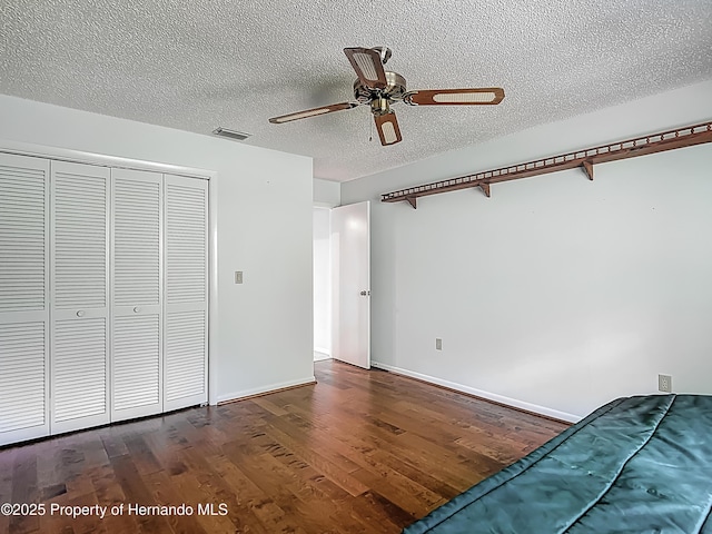 unfurnished bedroom with visible vents, a closet, wood finished floors, baseboards, and a textured ceiling