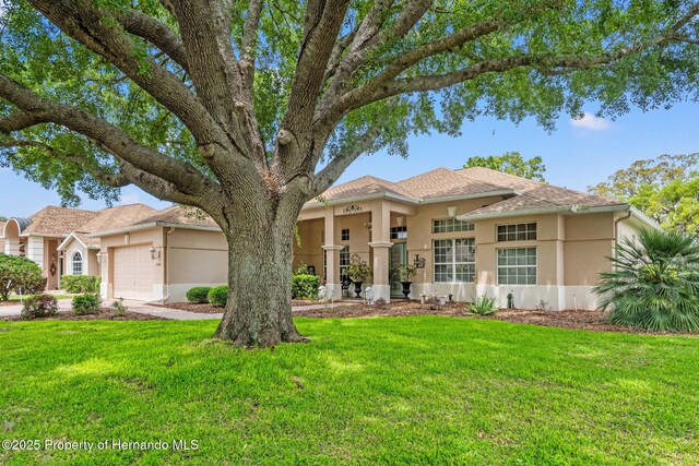 view of front of house with a garage, stucco siding, and a front lawn