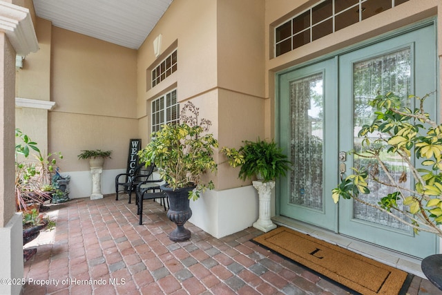 view of exterior entry with stucco siding and french doors