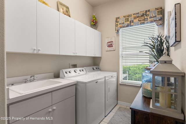 washroom with cabinet space, a sink, baseboards, light tile patterned floors, and washing machine and dryer