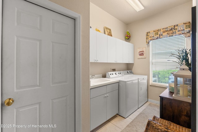 laundry area featuring baseboards, a sink, cabinet space, independent washer and dryer, and light tile patterned floors