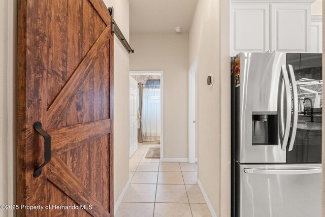 interior space featuring baseboards, a barn door, and light tile patterned floors