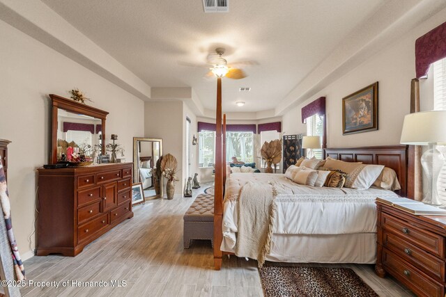 bedroom featuring visible vents, a ceiling fan, and light wood-style flooring