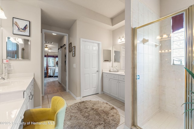 ensuite bathroom featuring tile patterned floors, two vanities, a sink, and a stall shower