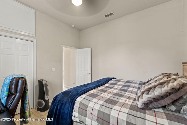 bedroom featuring a ceiling fan, visible vents, light wood-style flooring, and a closet