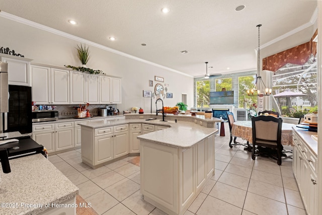 kitchen with a sink, a kitchen island with sink, light tile patterned floors, and stainless steel microwave