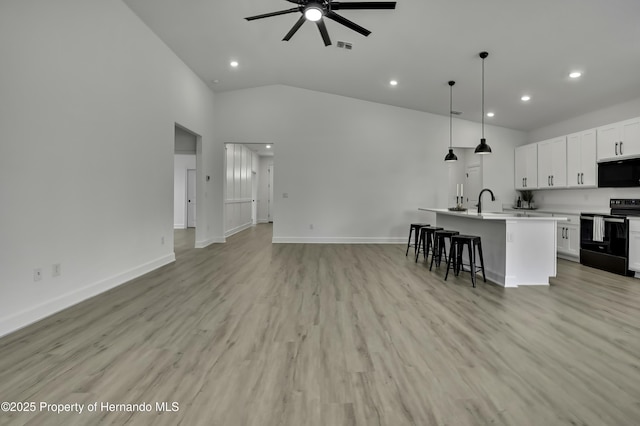 kitchen with an island with sink, a ceiling fan, open floor plan, recessed lighting, and black appliances