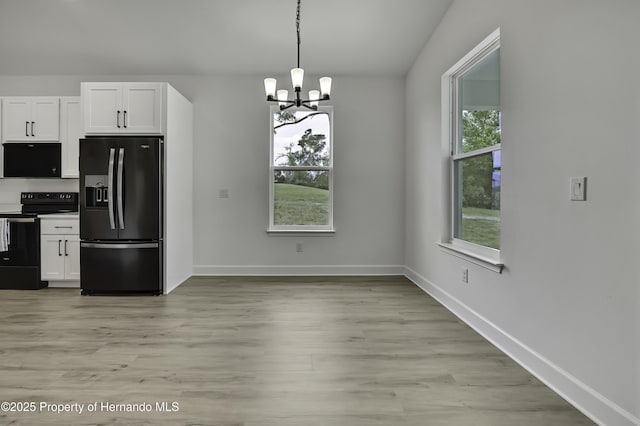 kitchen with light wood-style flooring, white cabinets, a notable chandelier, and black appliances