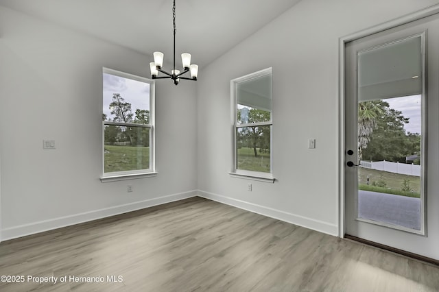 unfurnished dining area featuring baseboards, a chandelier, and light wood-style floors