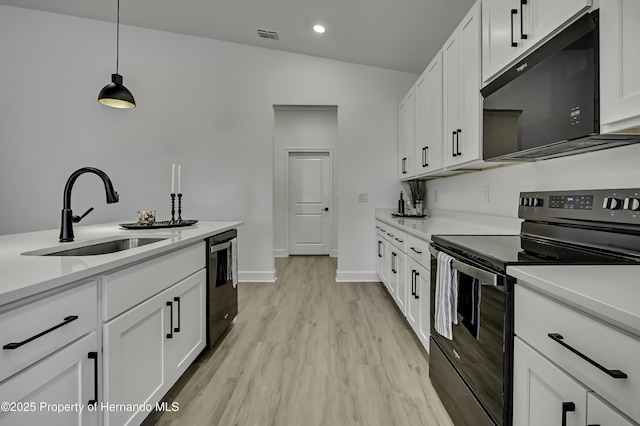 kitchen featuring white cabinets, a sink, light wood-style floors, light countertops, and black appliances