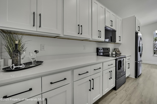 kitchen with light countertops, light wood-style flooring, white cabinetry, baseboards, and black appliances